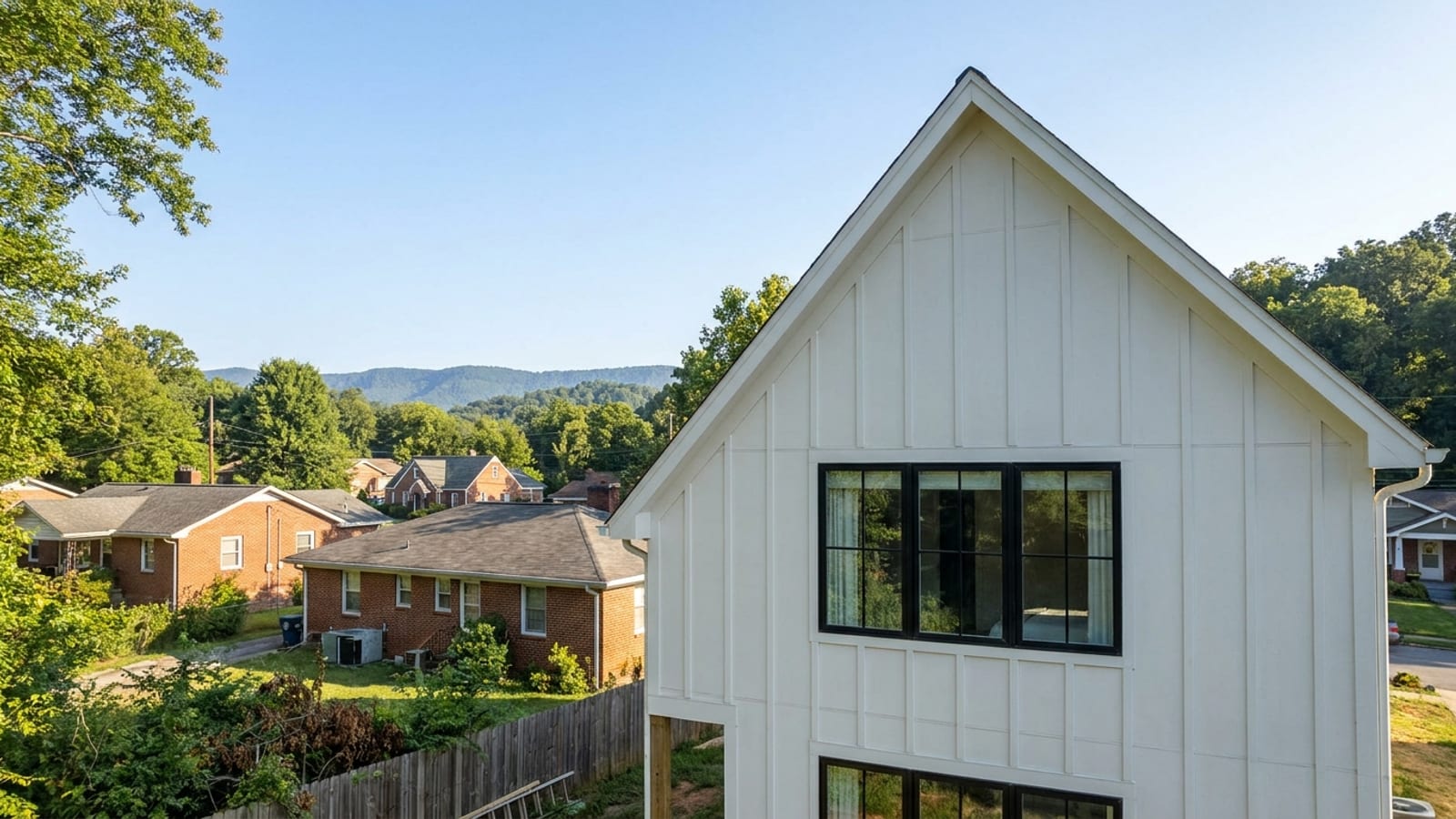 White vertical board and batten siding on a farmhouse gable with black-framed windows