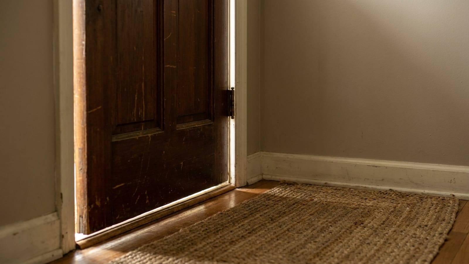 Daylight showing through the gap along the bottom and hinge side of an older wood entry door