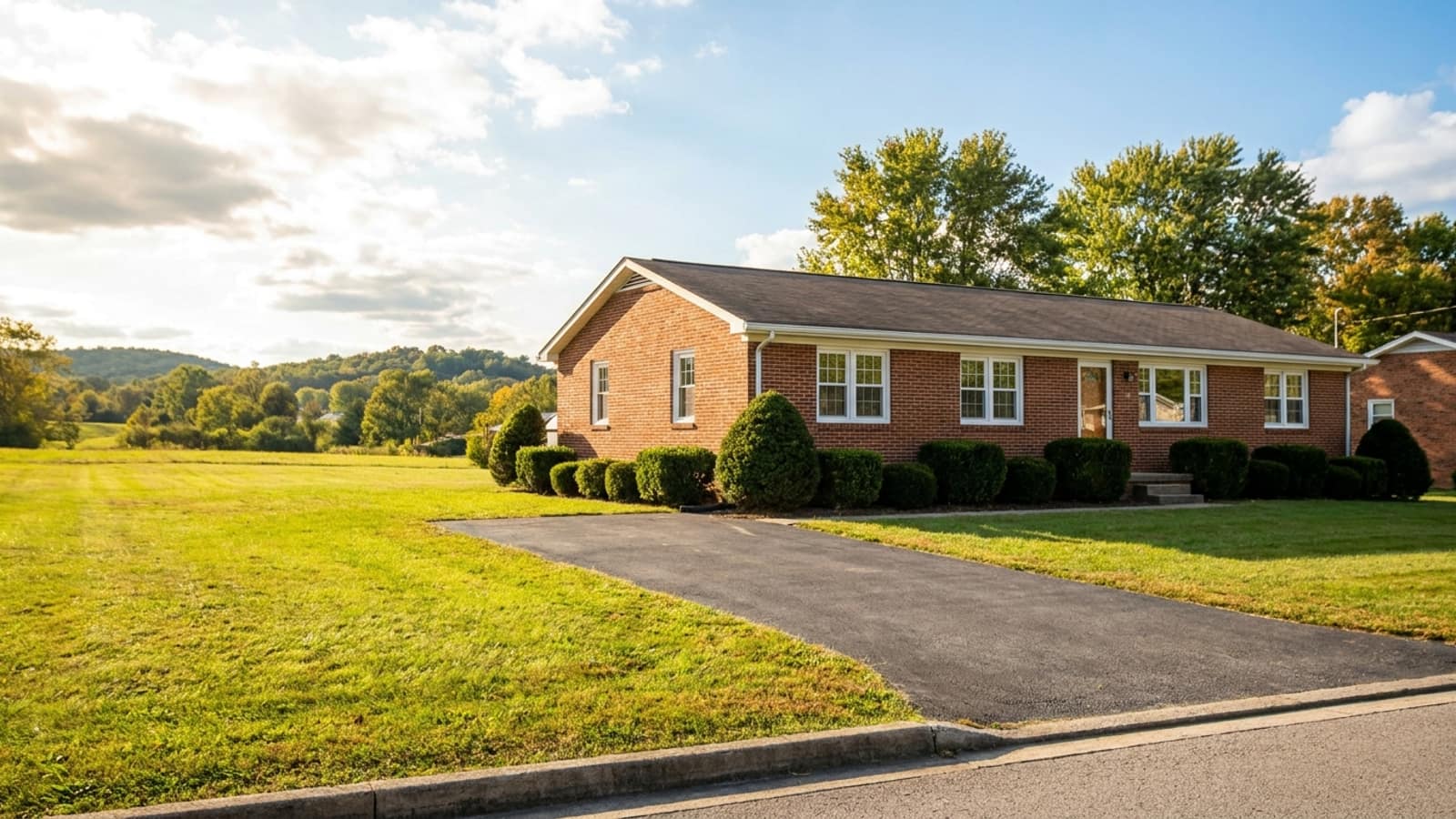Ranch home seen from the curb with new white replacement windows, trimmed shrubs and a clean driveway