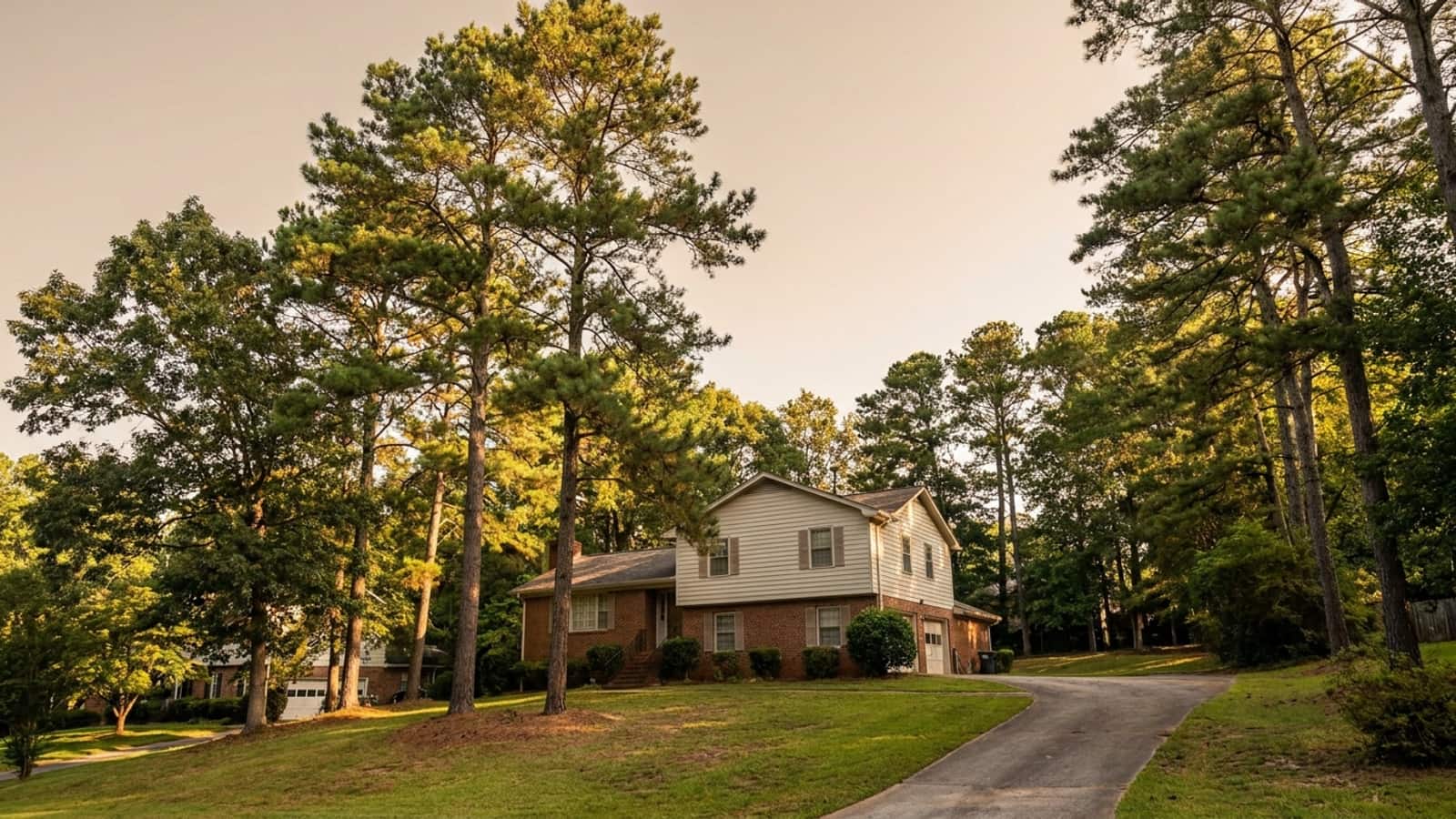 Two-story metro Atlanta home with brick on the lower level and lap siding above, surrounded by mature pines in morning light